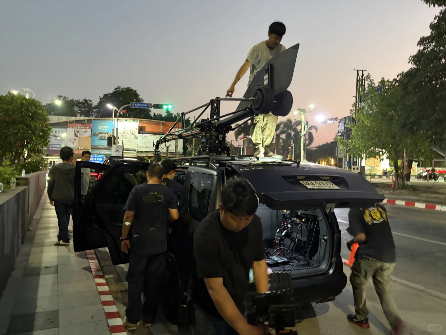 Camera crew preparing the roof-mounted camera arm on a tracking vehicle in Thailand.