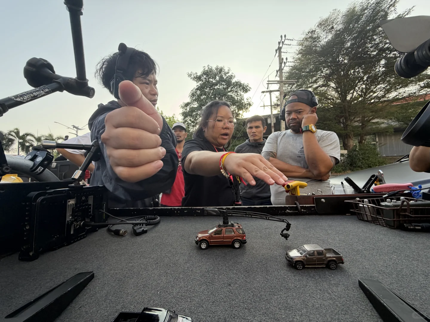 Camera team discussing vehicle positions with miniature cars beside the camera rig.